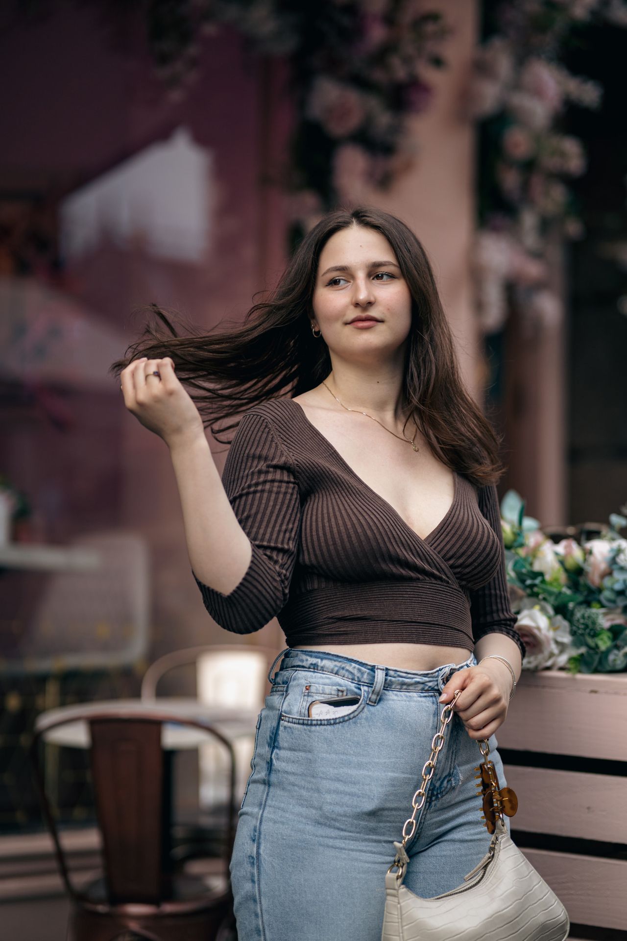 Outside a café with flower garlands, brushing the hair back in the breeze.