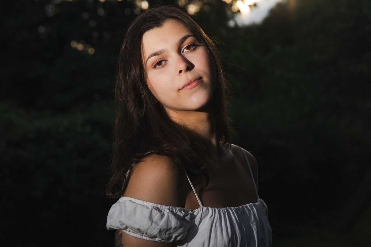 Against dark leaves, light falling on the shoulders and half the face.