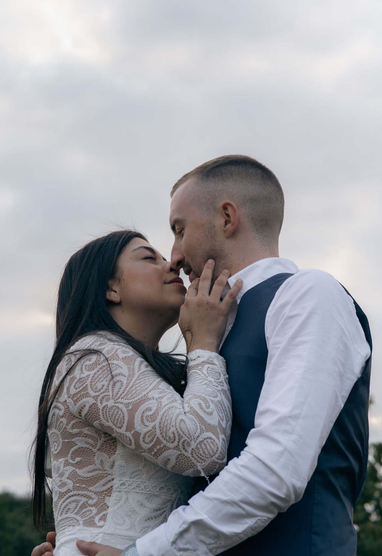 Nose to nose, about to kiss, one hand on the other’s cheek.
