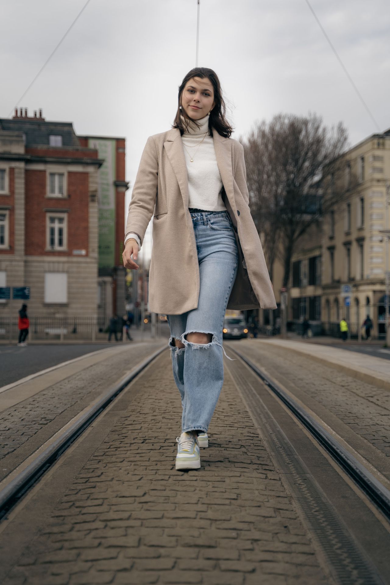 Walking down the middle of the tram tracks between brick and stone buildings.