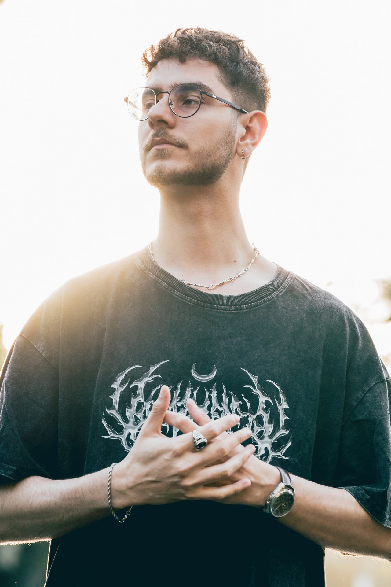 Hands clasped against a bright, hazy sky, looking into the distance.