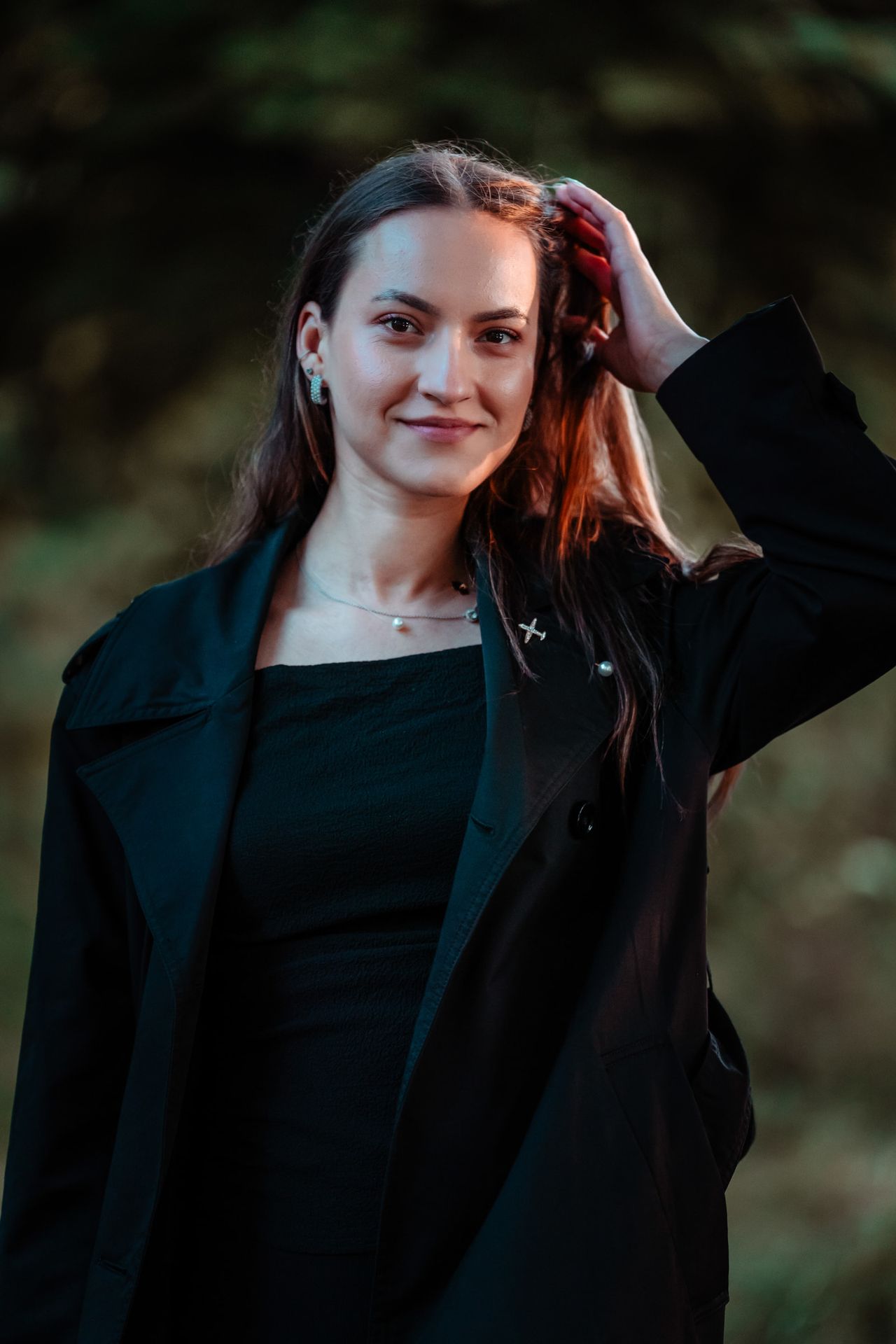 Close portrait with one hand in the hair, warm light on one side of the face.