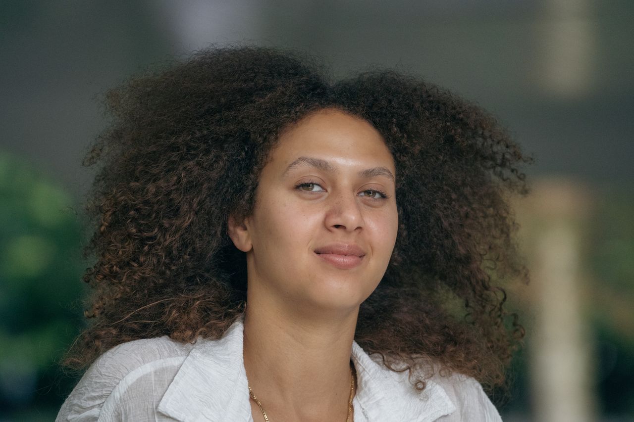 Head-and-shoulders portrait, curls framing a calm look straight at the camera.