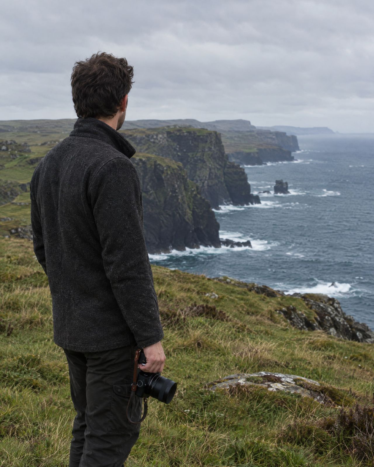 Temporary image of a photographer seen from behind, holding a camera on a coastal headland.